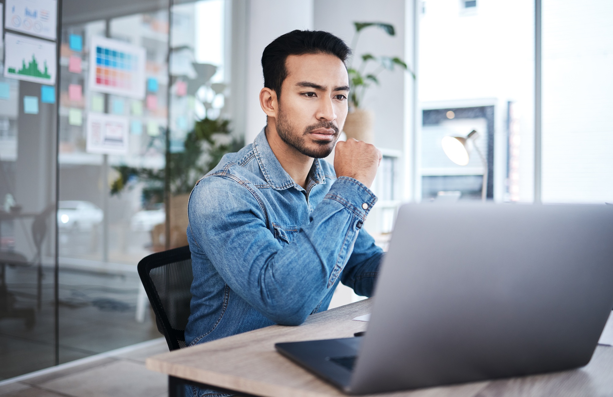 Thinking, laptop and man at desk reading email, website or research planning at design agency. Busi