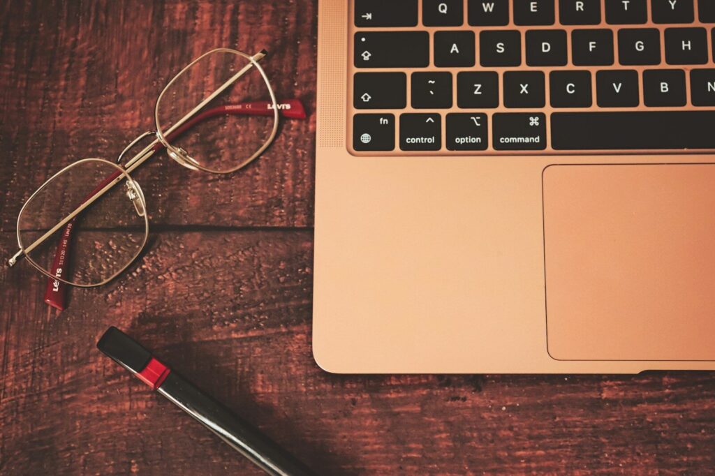 Pourquoi choisir Legalstart comme solution idéale pour votre accès à l’INPI Guichet unique ? a pair of glasses sitting on top of a wooden table next to a laptop computer