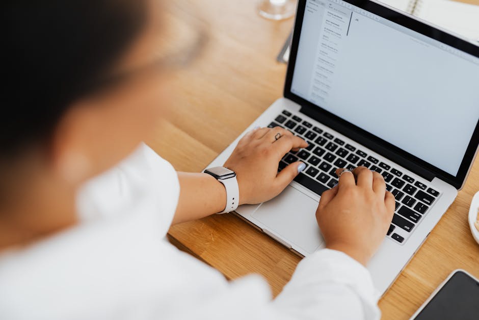 Person sending a professional email on a laptop in a modern workspace