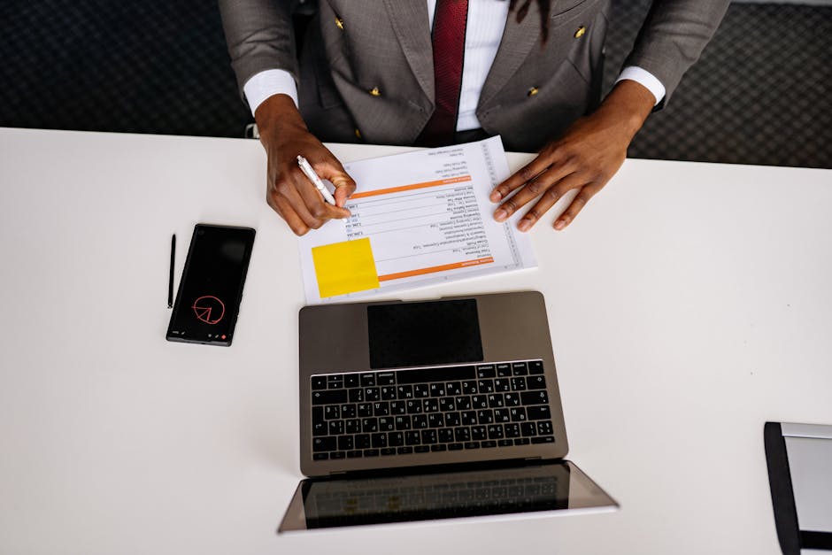 Professional writing a recommendation letter on a laptop with documents