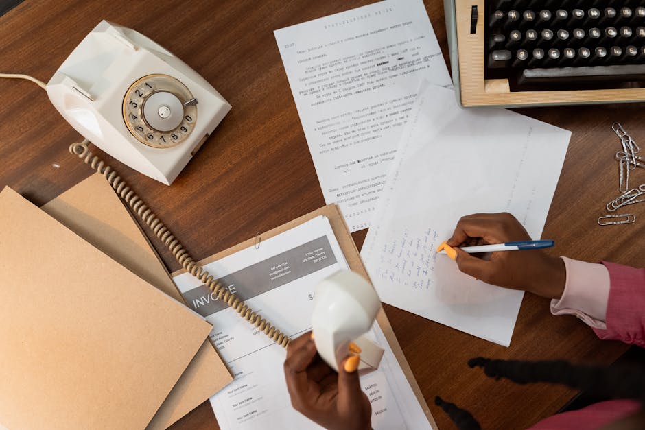 Person writing a professional letter with notes and documents