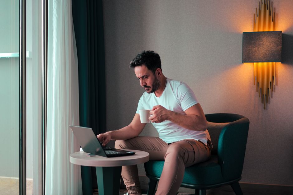 Experienced executive working alone in a hotel room with a laptop during a business trip