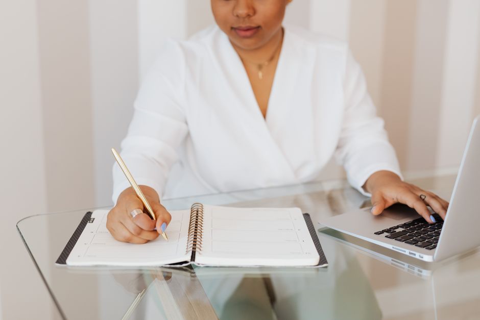 Personne en pleine réflexion professionnelle devant un carnet et un ordinateur portable