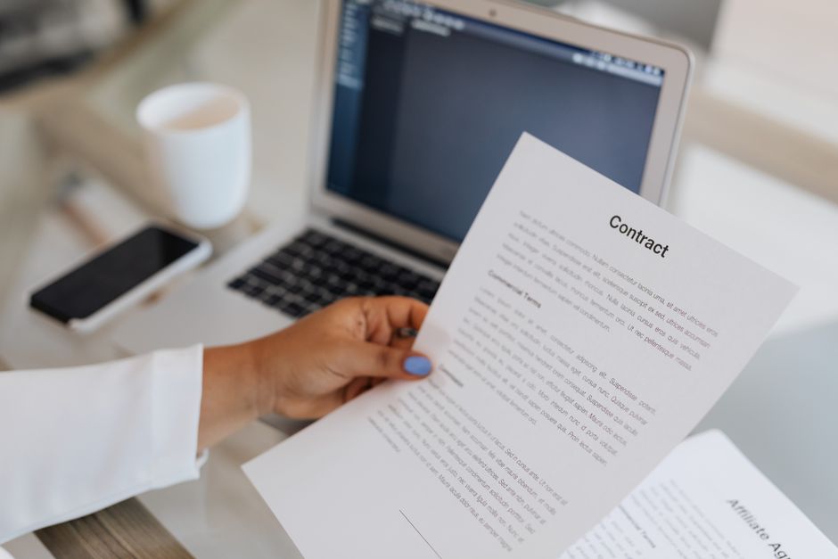 Employee reviewing a contract document at a desk with laptop