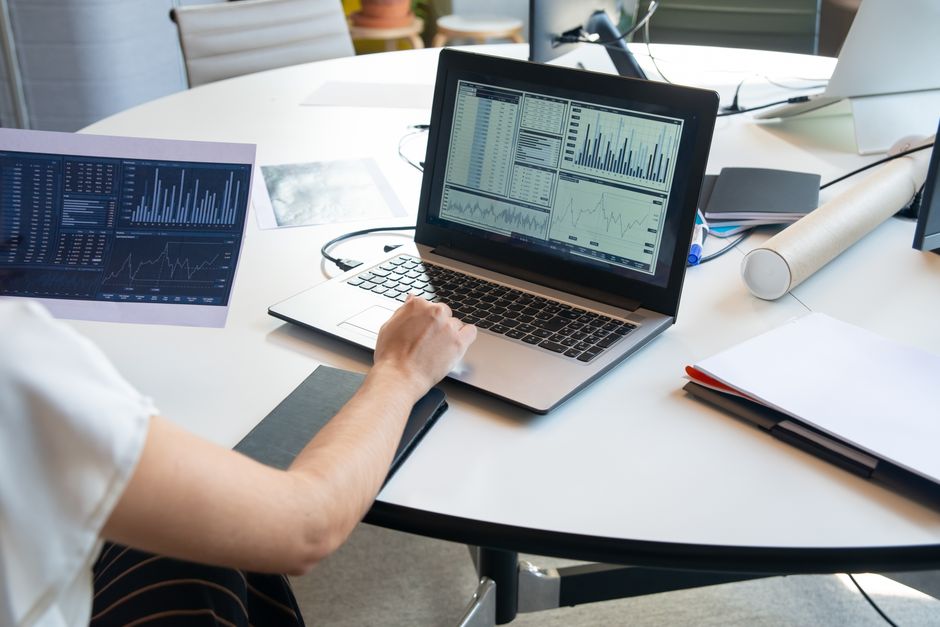 Chargé d'études analyzing data on a laptop with charts and reports
