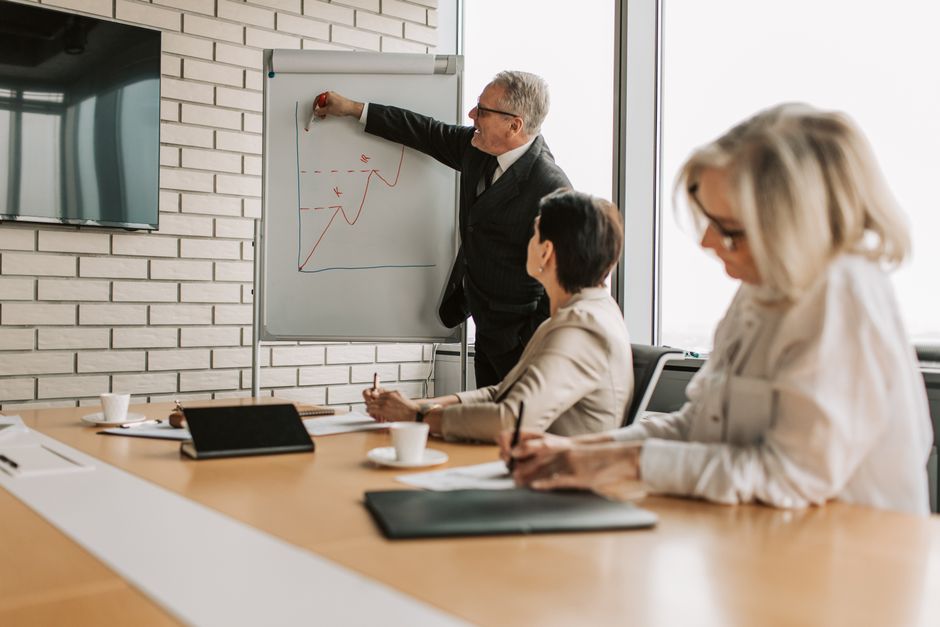Older employee in training session with notebook and laptop