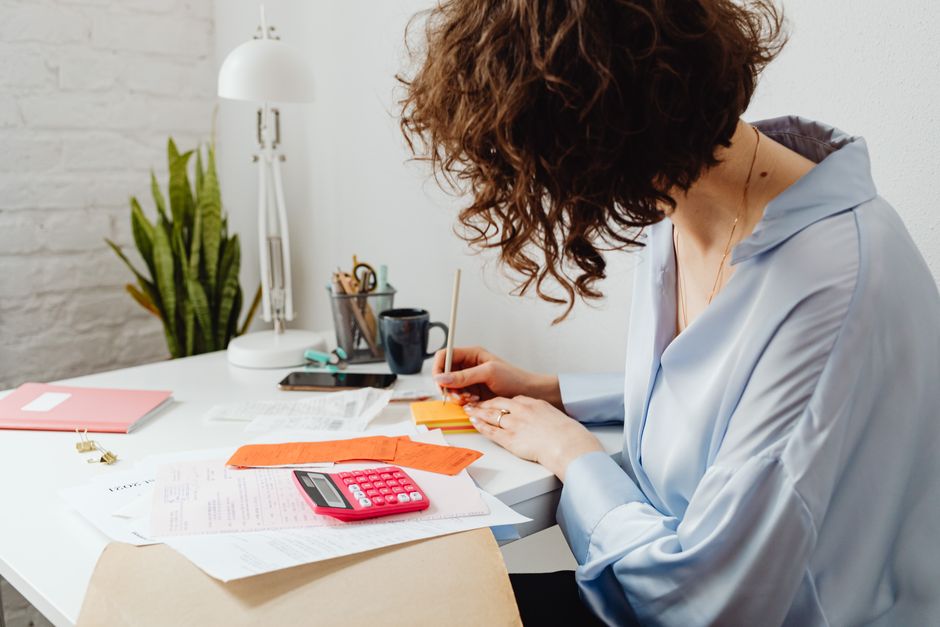 Person looking at unemployment paperwork and calculator on desk