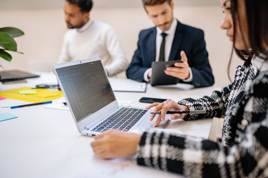 Business team meeting around a table with charts and laptops