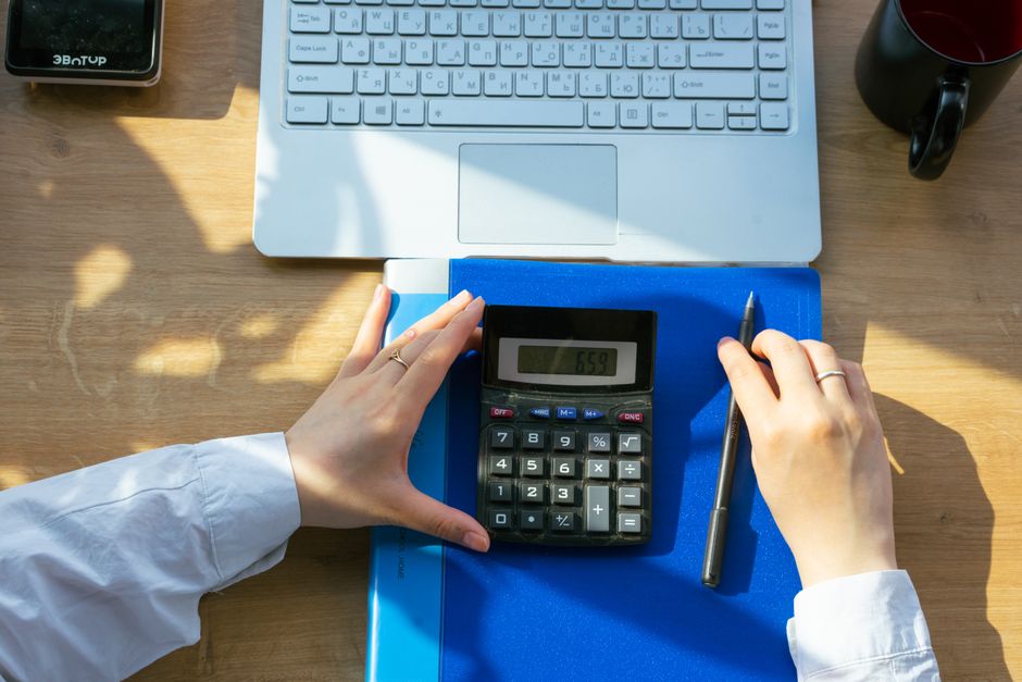 Person working late with laptop and calculator, overtime concept