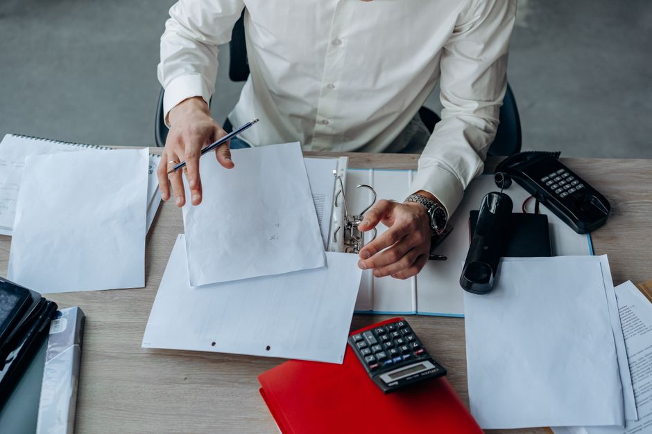 Préavis de démission : salaire maintenu, durée et dispense A business professional organizing documents at a busy office desk, emphasizing productivity.