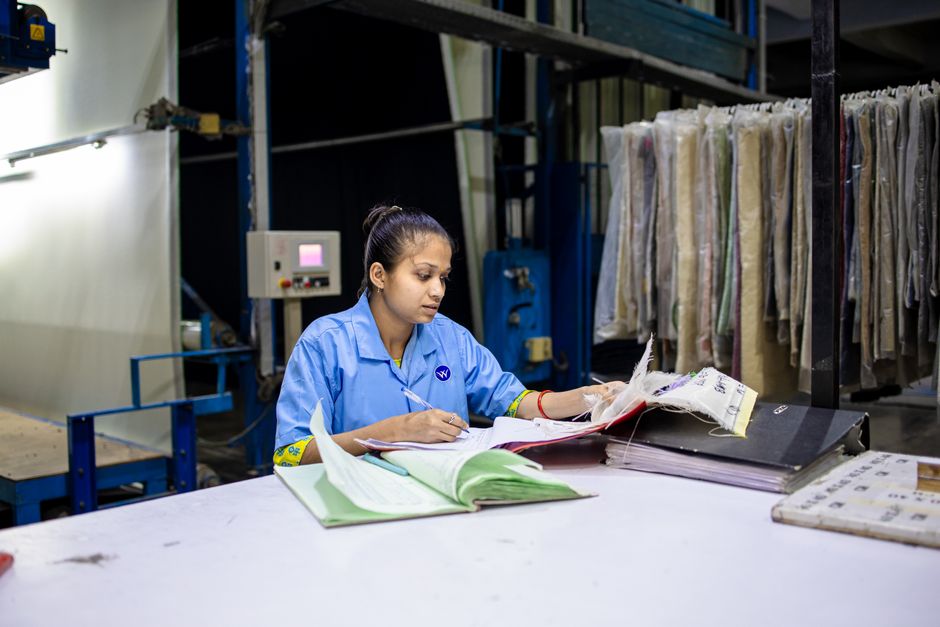 Job saisonnier : 8 vérifications, le salaire ne raconte pas tout A female textile worker in a factory reviews documents at a workstation.