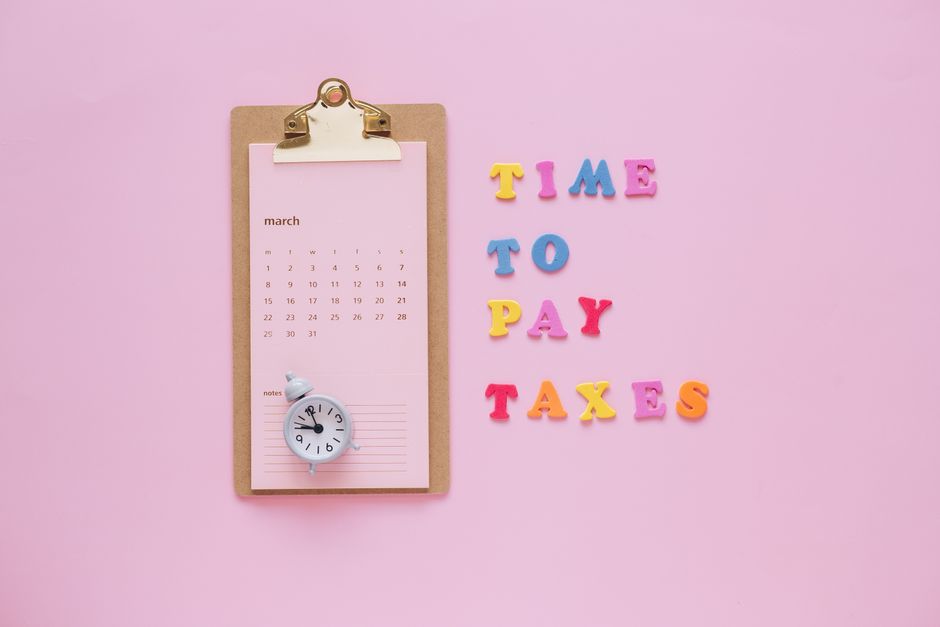 Cumul d’emplois : 48 heures, repos et impôt, le vrai calcul A flat lay of a March calendar and 'Time to Pay Taxes' letters on a pink background.