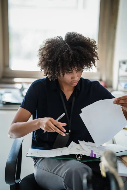 A professional woman reviews business documents, highlighting work focus.