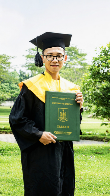 A proud graduate holds his diploma in a scenic outdoor setting.
