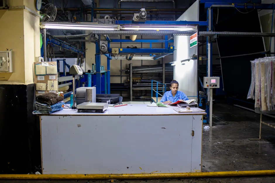 Congés payés : 25 ou 30 jours, le compteur ne ment pas A textile factory worker reading papers at a desk in an industrial setting.