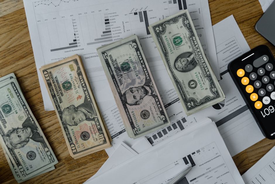 Salaire brut en net : 12 ou 13 mois, le calcul sans douche froide A workspace setup featuring cash, documents, and a calculator symbolizing financial analysis and budgeting.