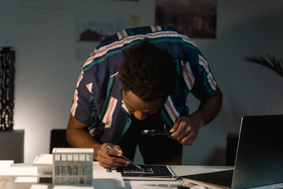 PPV 2026 : 3 000 ou 6 000 euros, le net à vérifier Architect examining blueprints with a magnifying glass in a modern office environment.