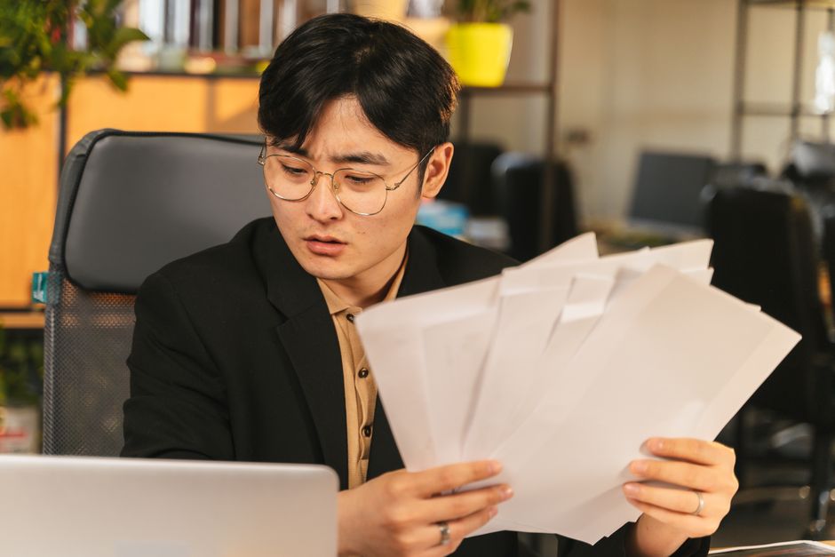Participation bloquée 5 ans : 14 cas pour la récupérer Businessman in glasses reviewing paperwork in a modern office setting.