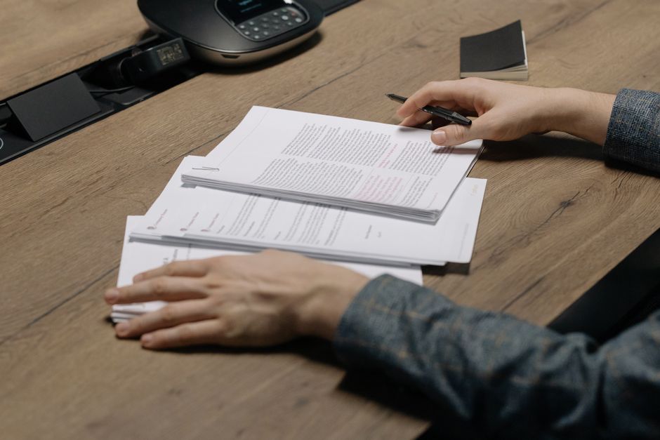 Prime d’objectifs : le bonus maximum peut être dû Close-up of a person reviewing documents with a pen at a modern office desk.