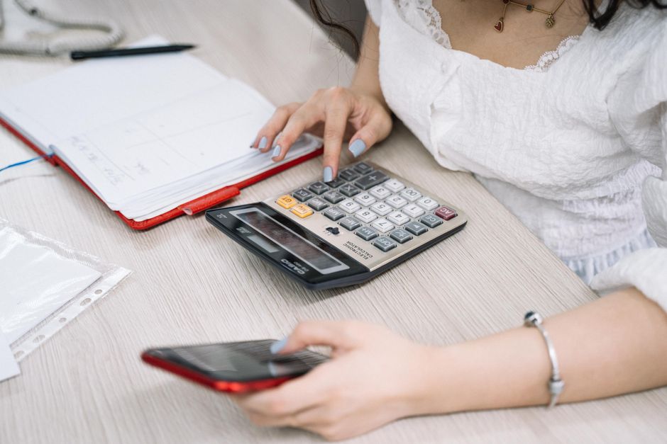 Temps partiel à 80 % : le salaire net baisse-t-il vraiment de 20 %? Close-up of a woman using a calculator and phone at her office desk.