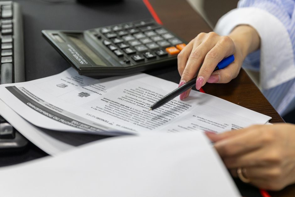 Conventions collectives 2026 : le SMIC monte, les grilles coincent Close-up of a woman's hand reviewing financial documents with a calculator.