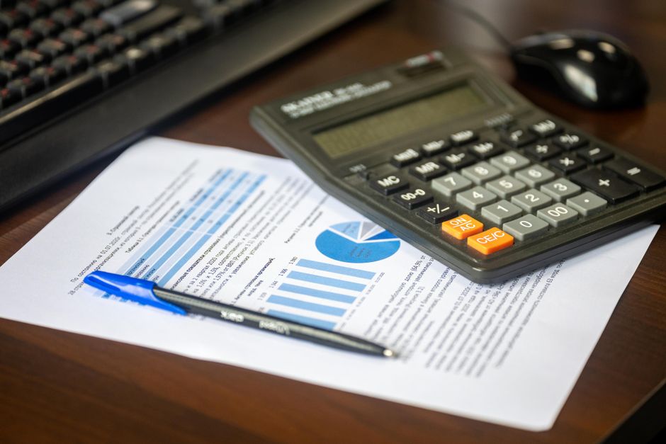 Salaire apprenti 2026 : 27 % à 100 % du SMIC, le piège de l’âge Desk with calculator, financial report, and pen, suggesting business analysis.