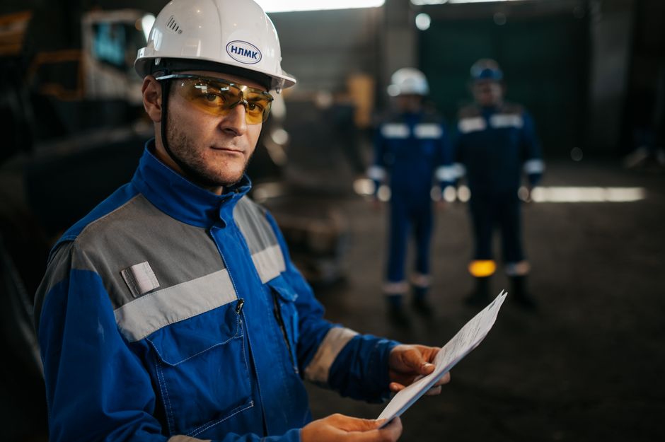 8 métiers sans diplôme au-dessus du SMIC en 2026, avec quelles contraintes? Focused industrial worker in protective gear reviewing documents in a factory setting in Russia.
