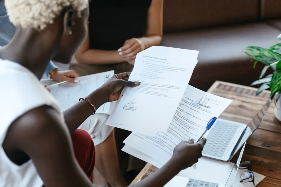 Cumul PEE et PER collectif en 2026 : 11 534 € d’abondement possibles, le piège est à la sortie From above of crop anonymous African American female comparing data in papers at table of office