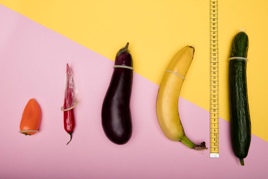 Fun conceptual photo comparing sizes of fruits using condoms and a measuring tape.