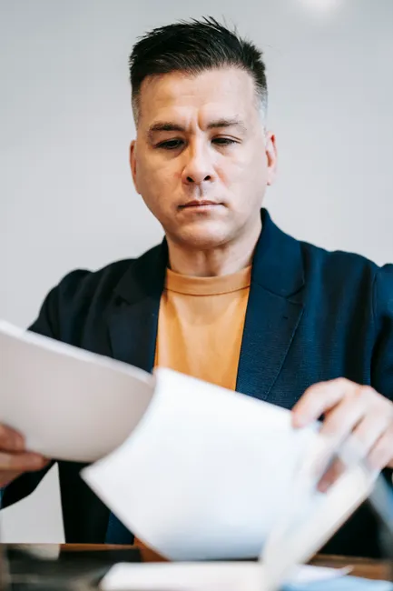 Man concentrating on paperwork in a professional setting, deeply engaged in reviewing documents.