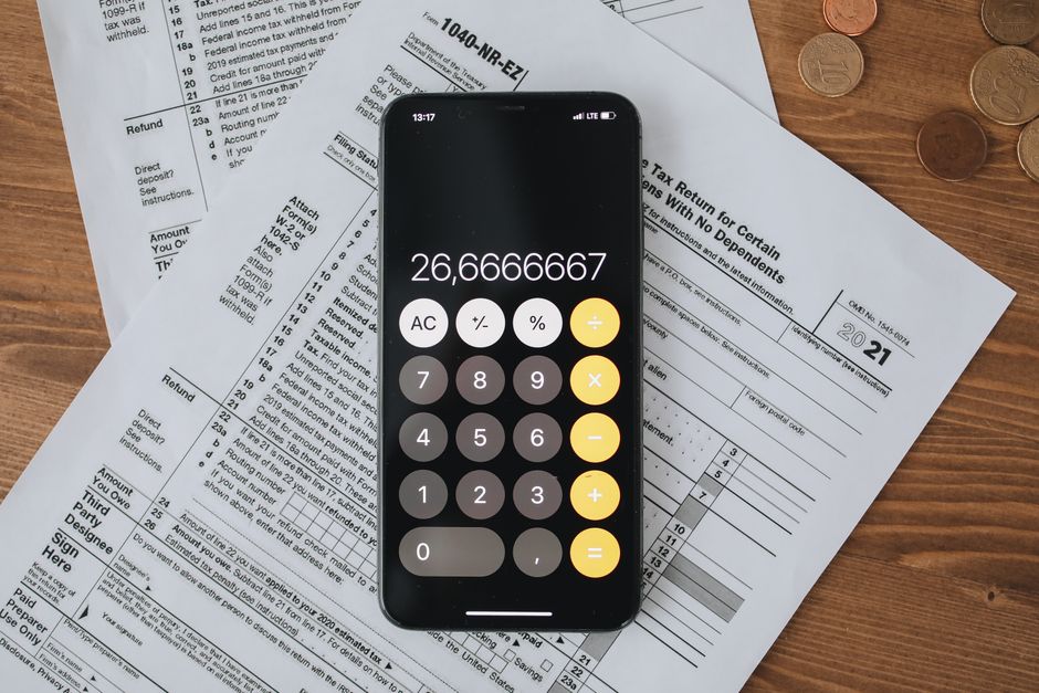 Trop-perçu d’impôt ou de salaire : qui rembourse, quand et comment? Mobile calculator app on tax documents, highlighting financial calculations and tax preparation.