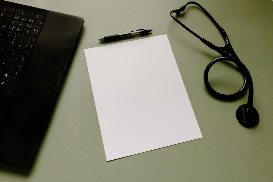 Fiche de paie aide-soignante de nuit : 2 105 € net, le détail compte Professional workspace featuring a laptop, stethoscope, pen, and paper sheet for healthcare tasks.