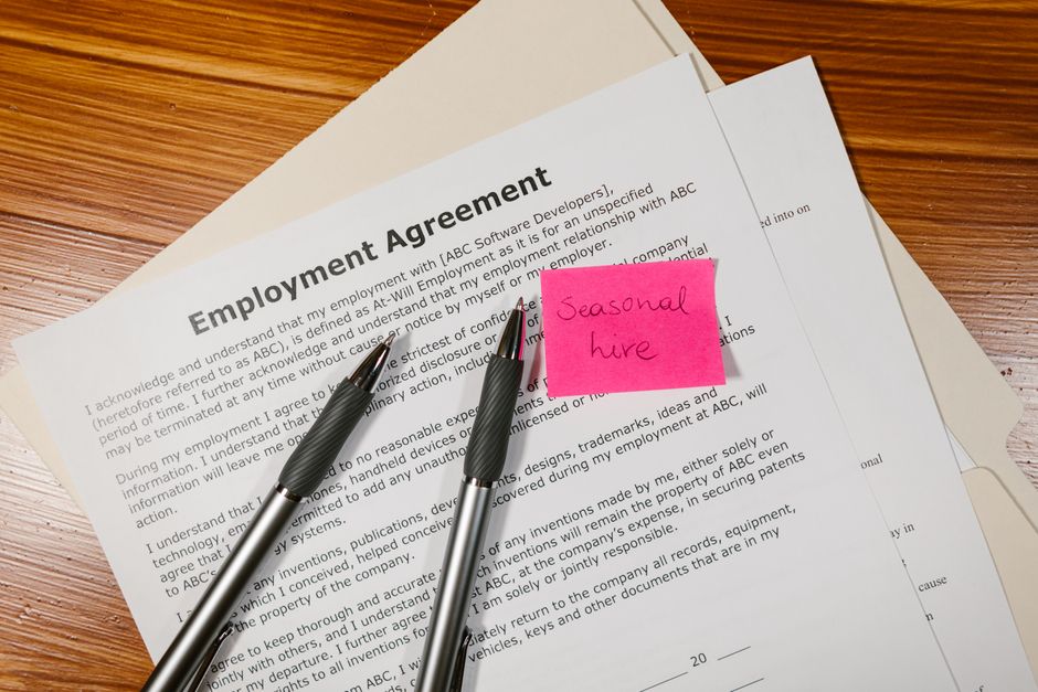 CDD ou CDI : 10 % de prime, mais le net mensuel ne suit pas Top view of employment agreement contract with pens and seasonal hire note on wooden desk.